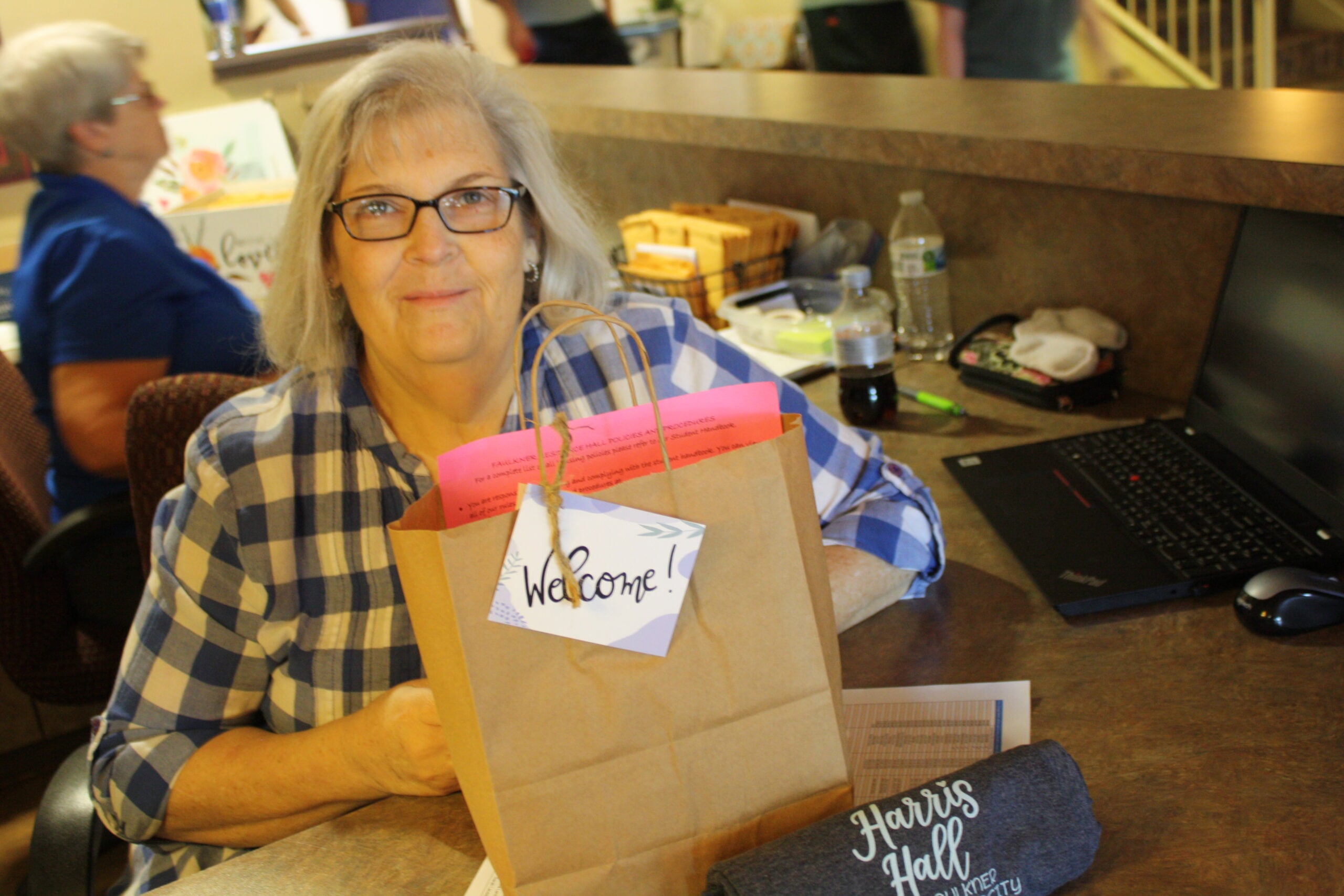 Peggy  Oliver sits at the front desk of the women's dormitory with a gift bag to welcome freshmen girls to their new home away from home.