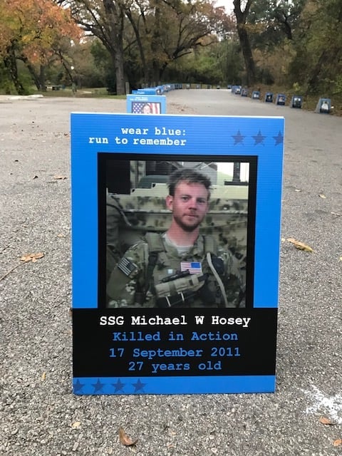 A Picture of SSG Michael Hosey in his combat fatigues is set in a blue frame and placed along a portion of the race pavement.