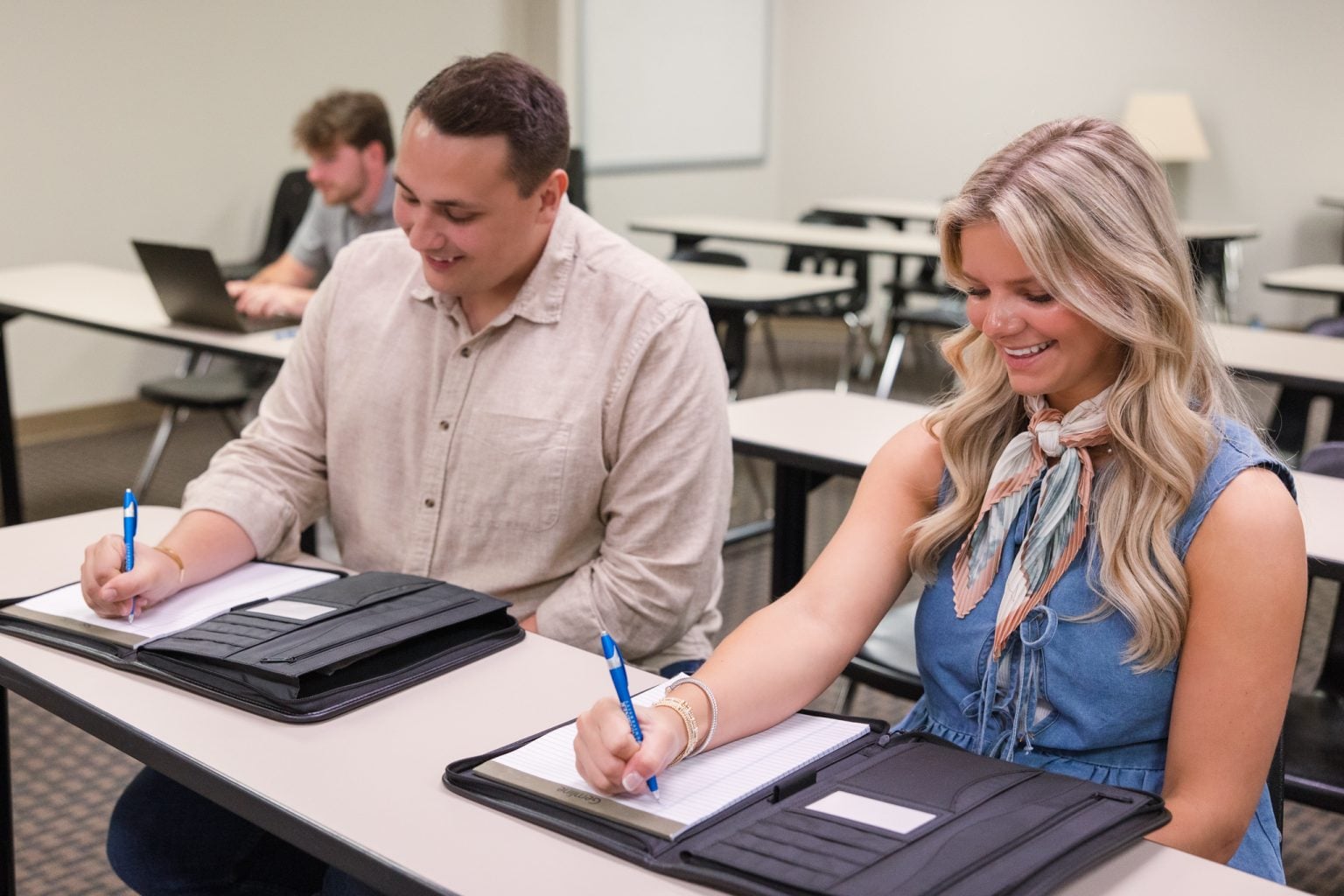 Two students writing in notebooks.