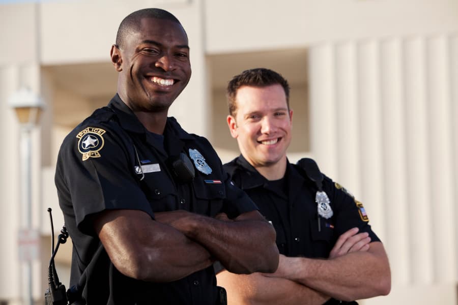 Two police officers crossing arms and smiling.