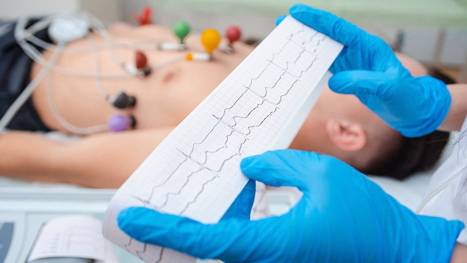 Photo of a doctor reading an EKG with a patient in the background
