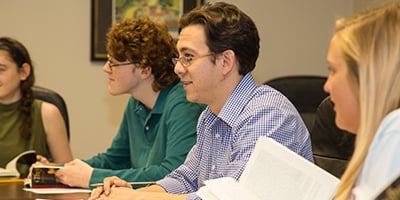 A teacher and students discussing a book in a classroom