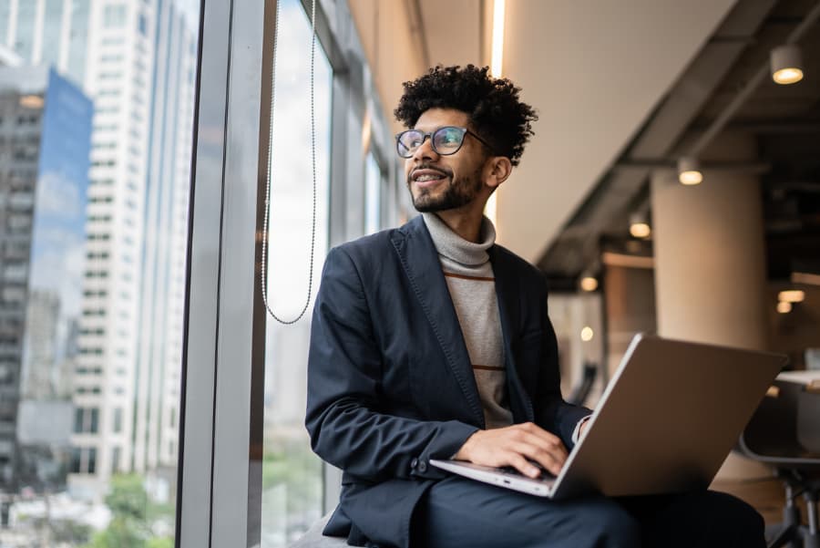 Businessperson with computer looking out window