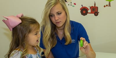 Health Sciences student showing a little girl a green block