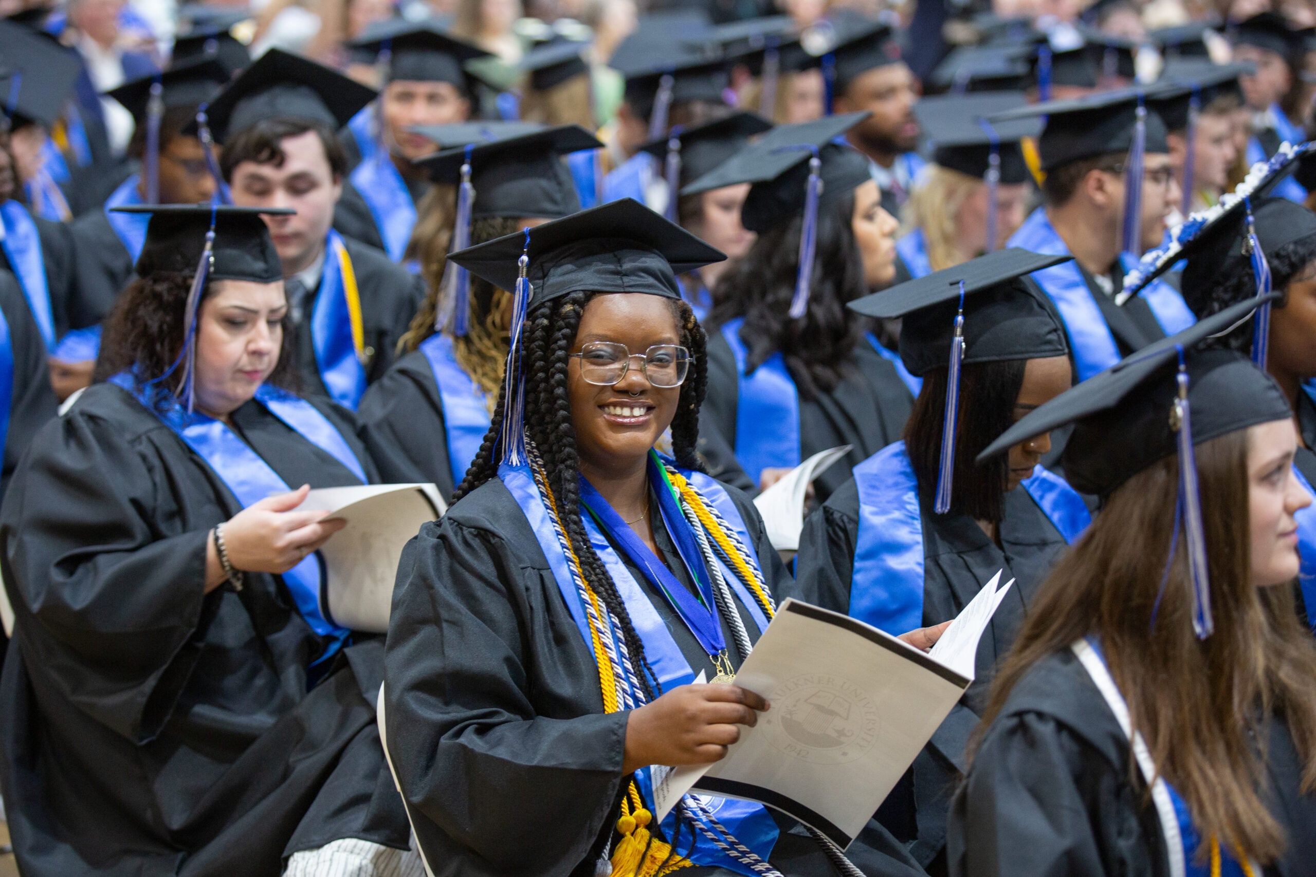 Student in cap and gown smiling in graduation ceremony