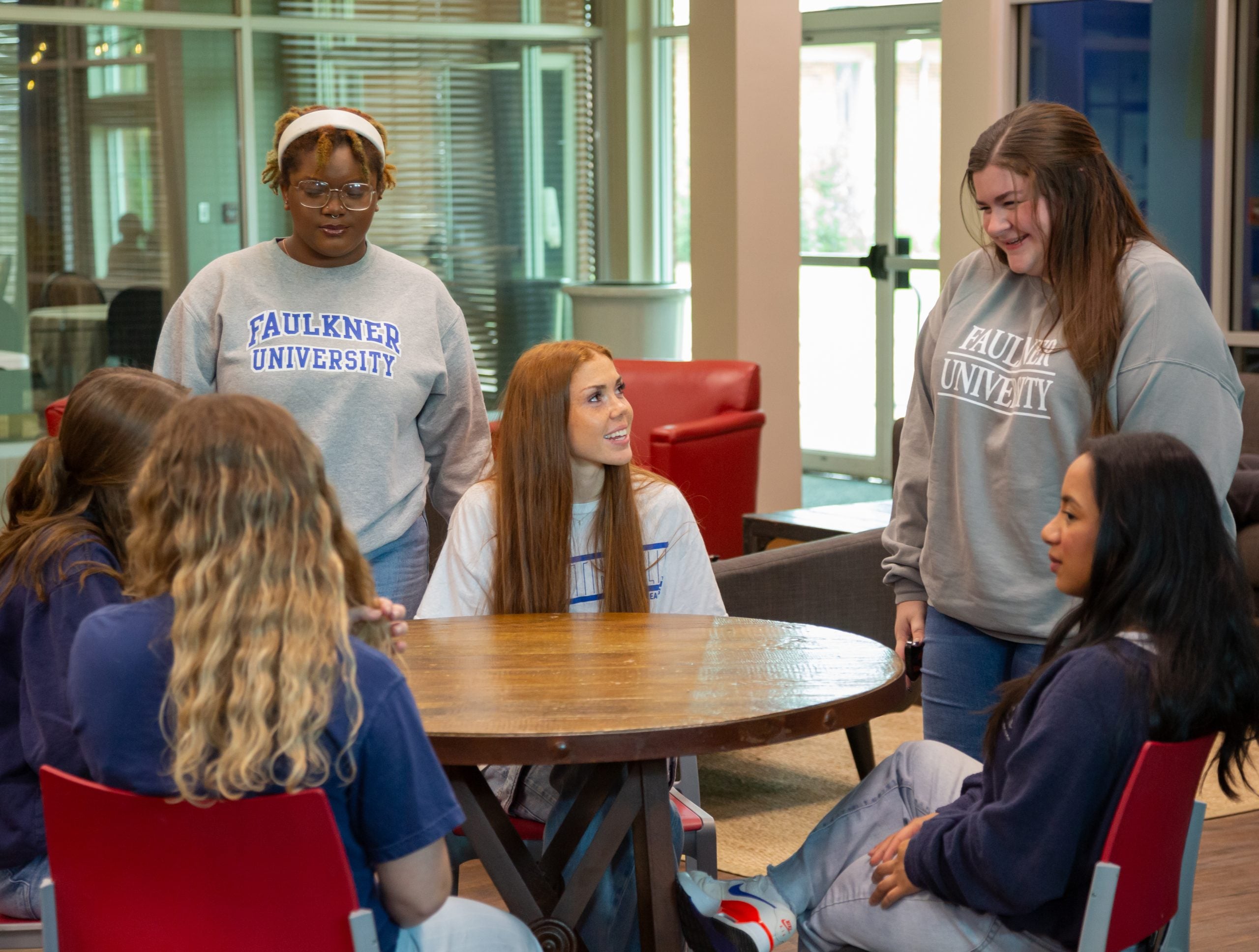 several students standing around table talking
