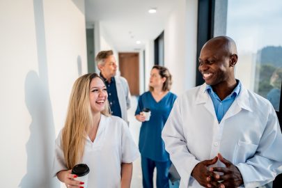 Doctor and assistant smiling while talking and walking