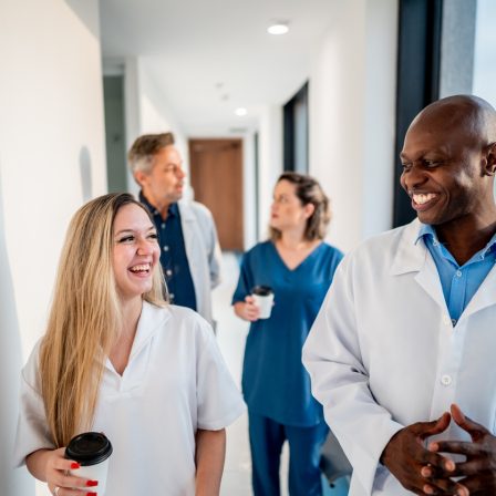 Doctor and assistant smiling while talking and walking