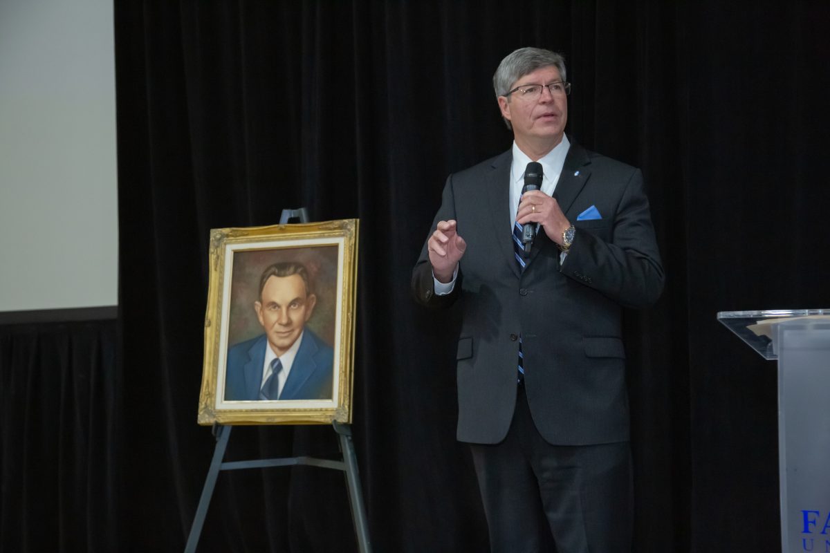 President Mitch Henry stands by a painting of Joe Greer.