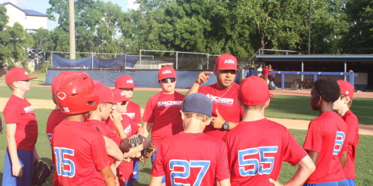 Jonathan Villa talks with a group of children with Anchor baseball.