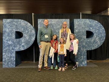 Matt Wallin, left, stands with his wife and children in front of the letters PTP.