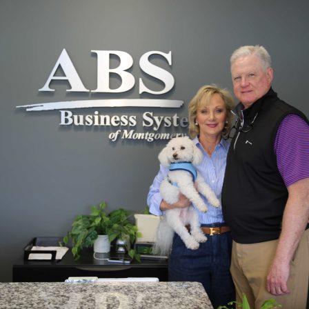 l-r Judy and Eddie Cobb stand in front of the ABS logo. They are supporters of the Zorn Scholarship Fund.