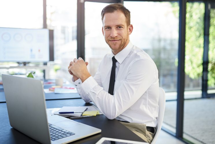 Portrait of a businessman working on a laptop in a modern office.